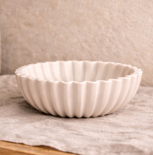 White resin bowl with grapes on a wooden surface