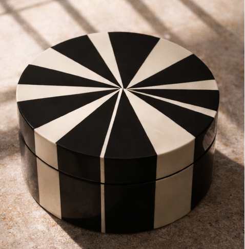 Black and white geometric-patterned box on a dark surface with a neutral background