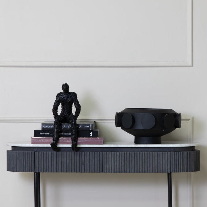 A resin large pedestal bowl with black cylinders on the exterior or perimeter