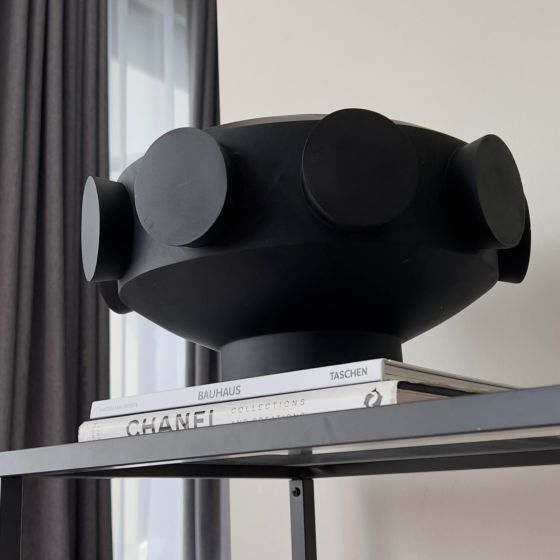 A resin large pedestal bowl with black cylinders on the exterior or perimeter