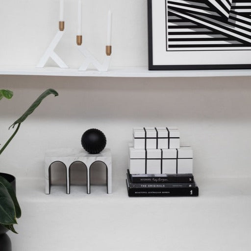 Storage white boxes with grid lines embossed stacked on each other, placed on a shelf with other objects 